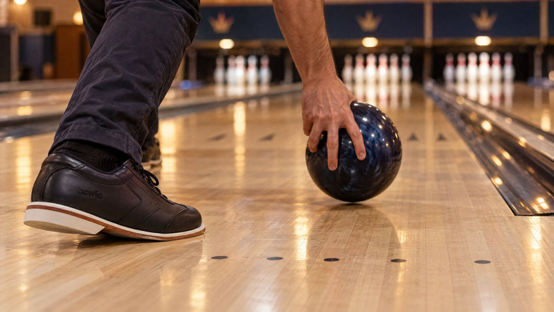 Hånd slipper kuglen i ankelhøjde ved siden af en BOWLIO Nero bowlingsko