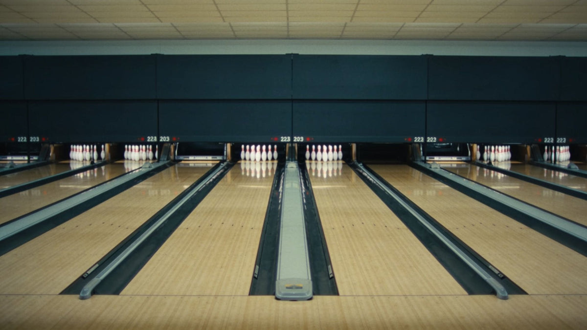 Row of bowling lanes with the pins set up, seen from behind the approach