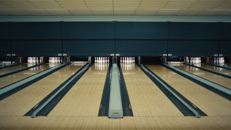 Række af bowlingbaner med rejste kegler, set bag tilløbet